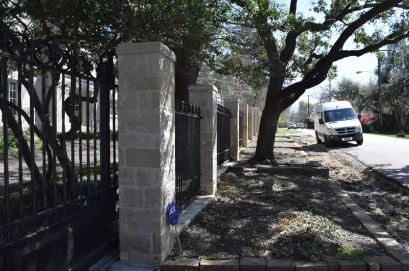 Residential black metal fence with brick posts