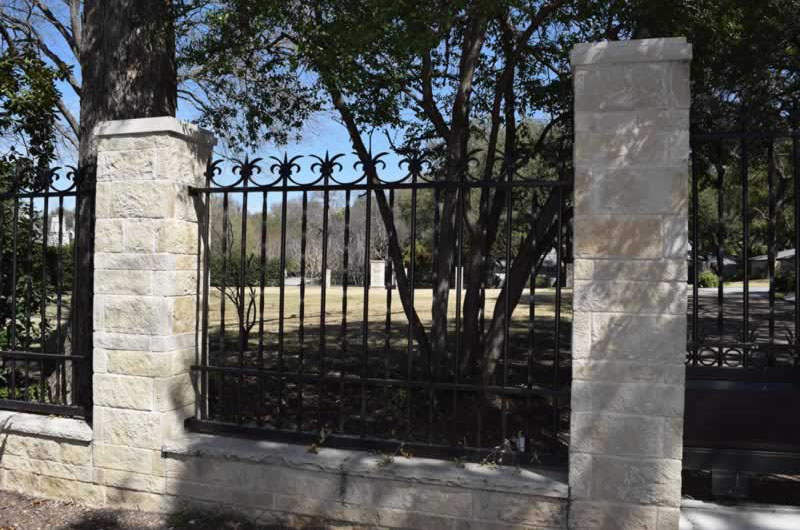 Residential black metal fence with brick posts