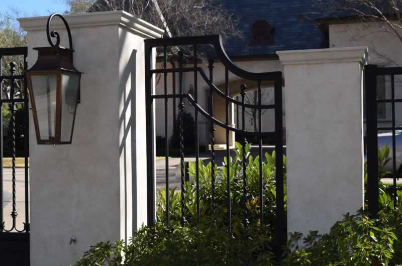 Residential black metal fence with stone posts and a lantern