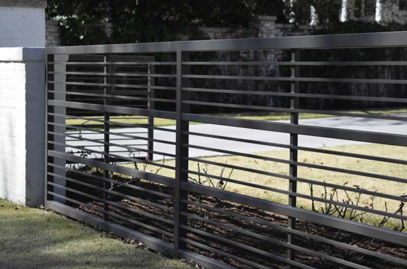 Residential black metal fence with stone posts