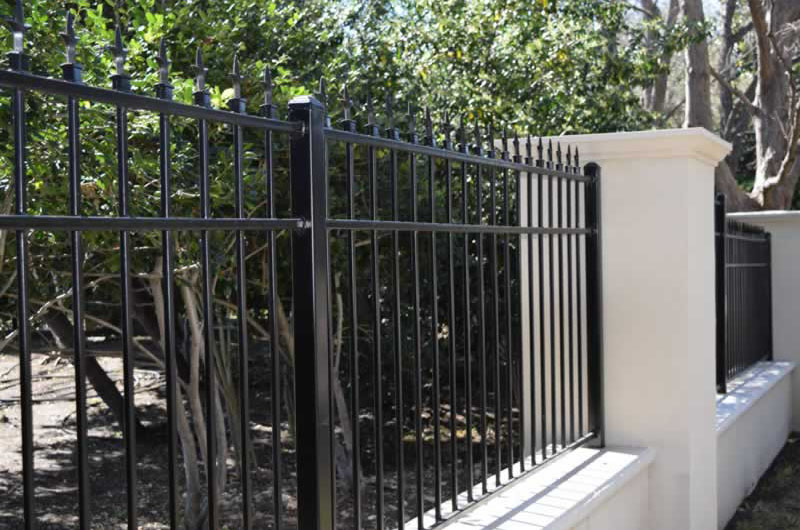 Residential black metal fence with stone posts