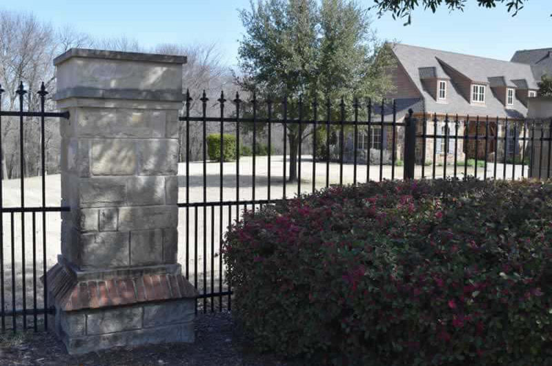 Residential black metal fence with brick posts