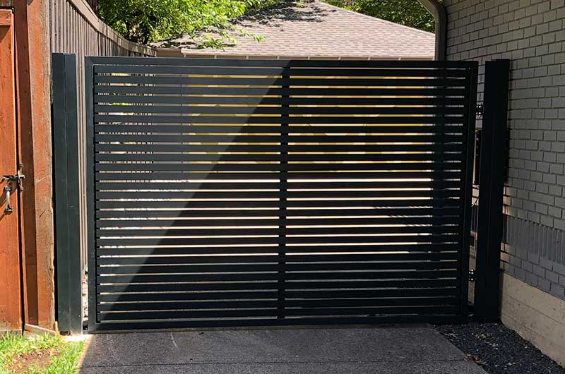 Residential swinging gate with black metal fence