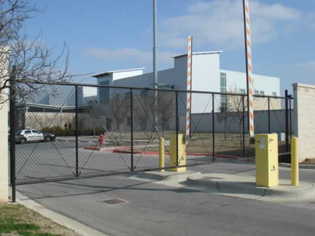 Metal bar gate with wooden fence and gate operator